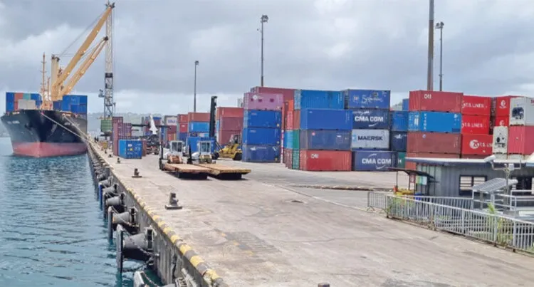 A photograph of a cargo ship in the water next to shipping crates at the Fiji Ports Terminal Limited in Suva.